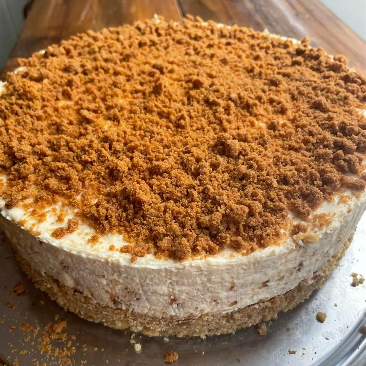 Whole cheesecake on a biscuit base, thickly topped with golden biscuit crumb